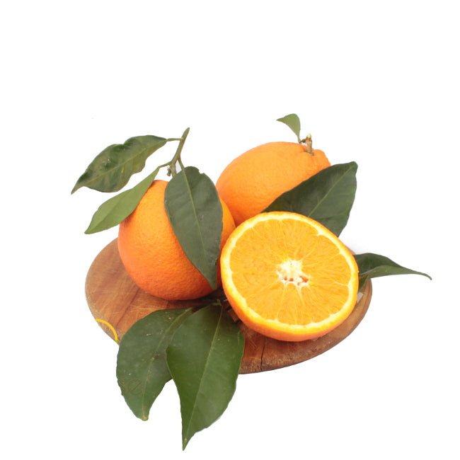 Cassetta di arance lucane Navel, mature e dal colore arancio intenso, con buccia lucida e polpa succosa. Le arance sono disposte su un tavolo rustico di legno, illuminate da una luce calda che esalta la loro freschezza e naturalezza.