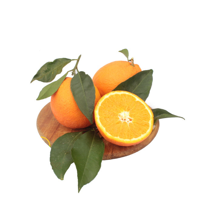 Cassetta di arance lucane Navel, mature e dal colore arancio intenso, con buccia lucida e polpa succosa. Le arance sono disposte su un tavolo rustico di legno, illuminate da una luce calda che esalta la loro freschezza e naturalezza.